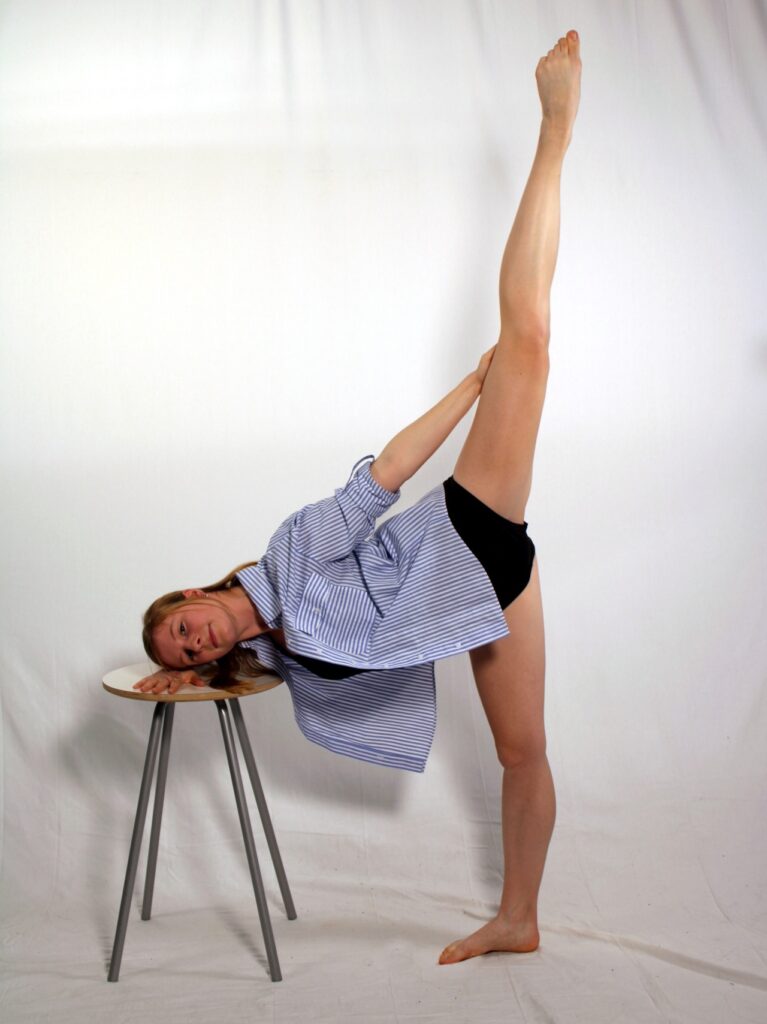 Caroline in a ballet pose with one foot high in the air behind her