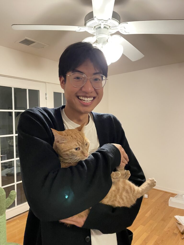Tytus smiling hold an orange cat